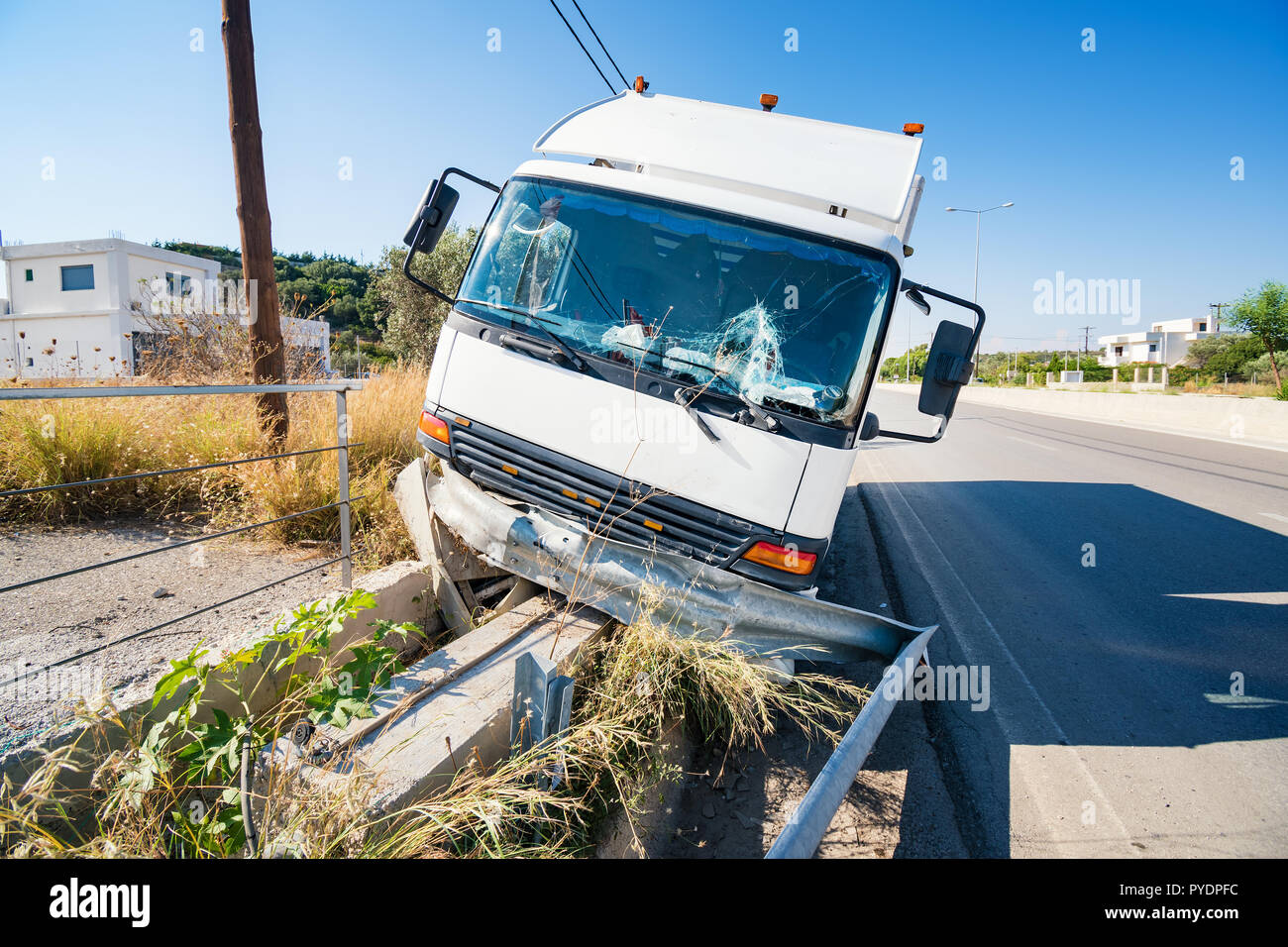 Front of crashed truck that hit crashed barrier on the road, broken windshield, sunny day Stock Photo