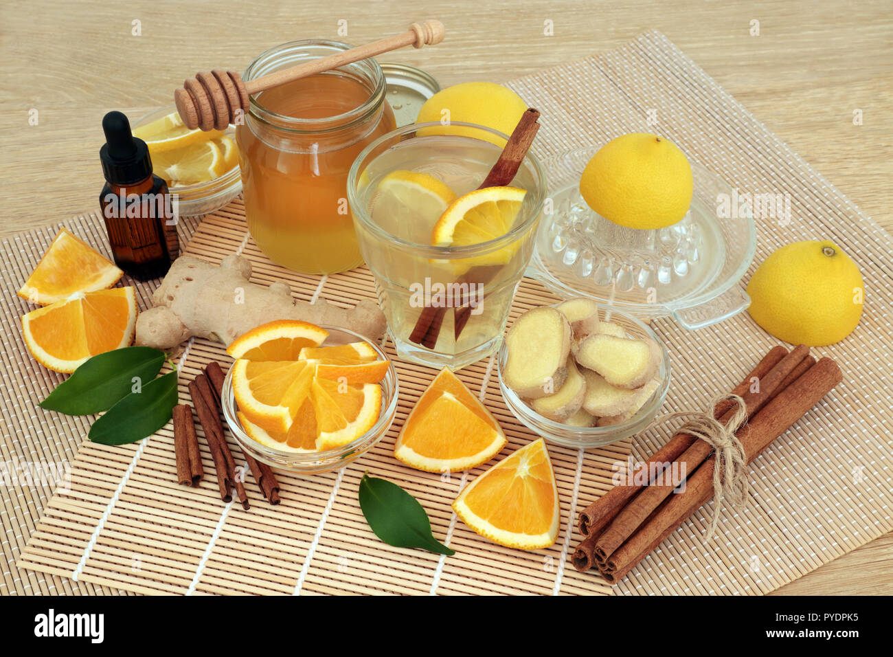 Ingredients for cold and flu remedy with ginger and cinnamon spice, eucalyptus aromatherapy oil, orange &lemon fruit with honey drink on bamboo mats. Stock Photo