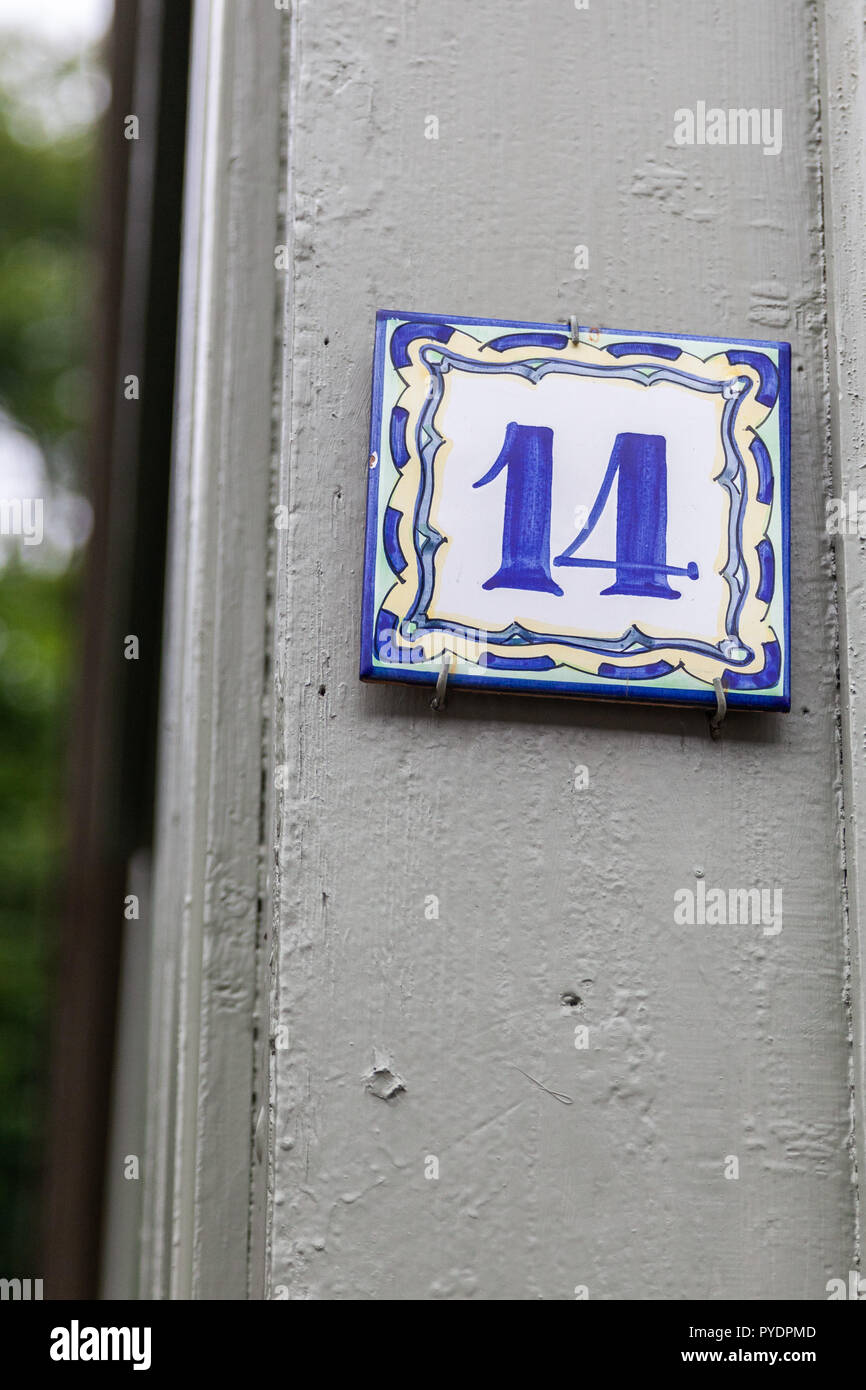 House number fourteen 14 painted on ceramic tile in blue and yellow from Sweden Stock Photo
