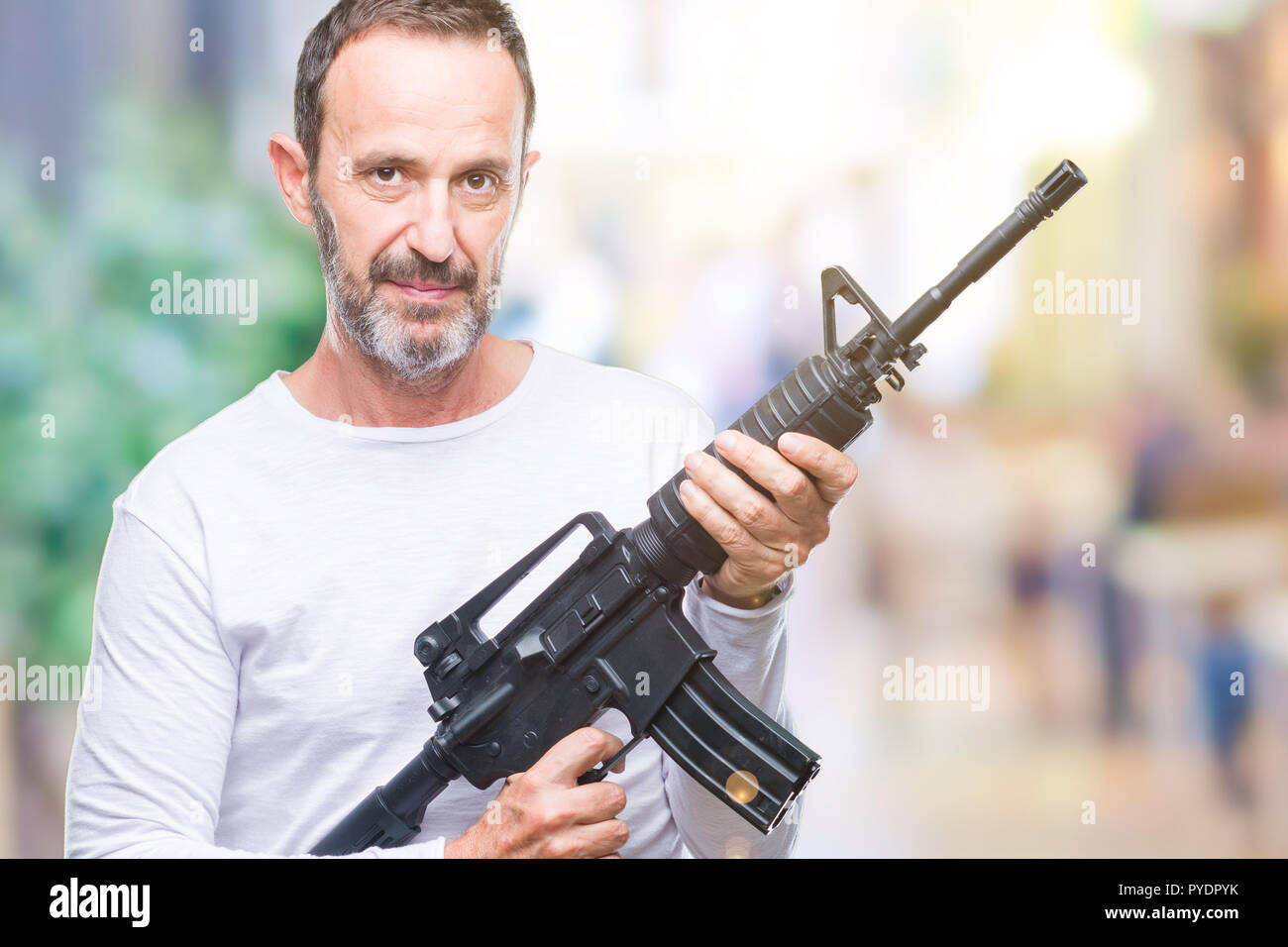 Middle age senior hoary criminal man holding gun weapon over isolated background with a confident expression on smart face thinking serious Stock Photo
