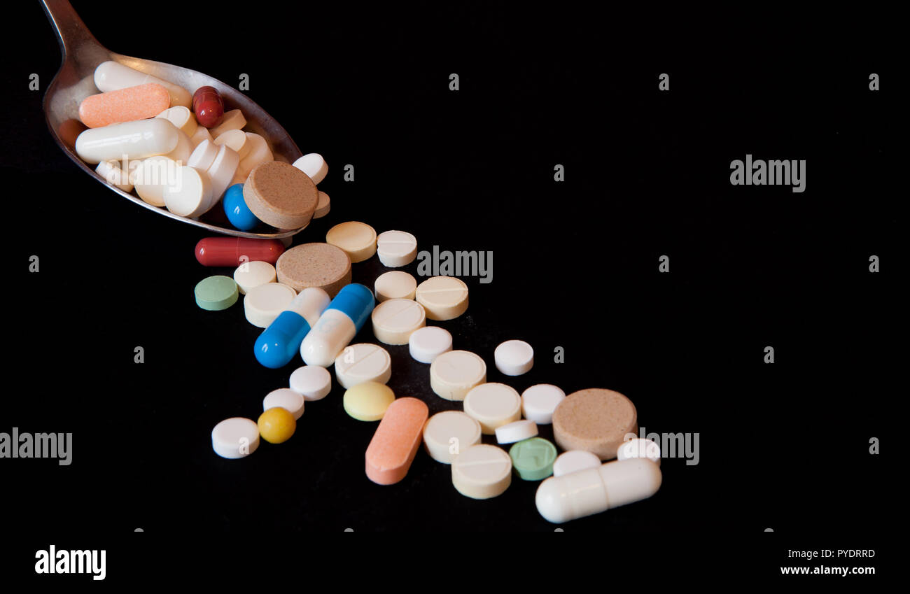 Pharmacy background on a black table. TTablets with a spoon. Pills. Medicine and healthy. Close up of capsules. Different kind of pills Stock Photo