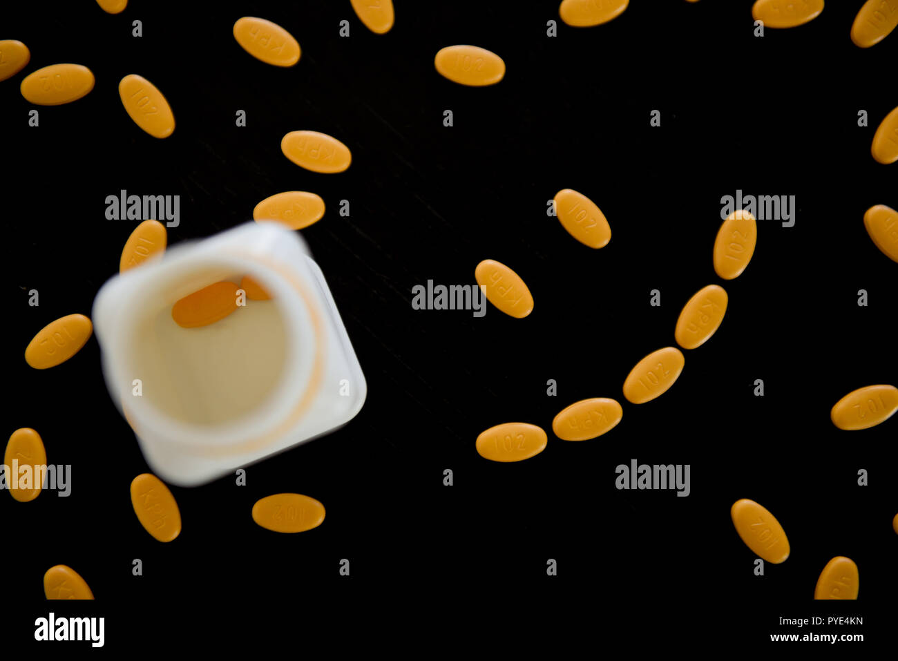 Smiley face made out of yellow spiral pills on the black table ...
