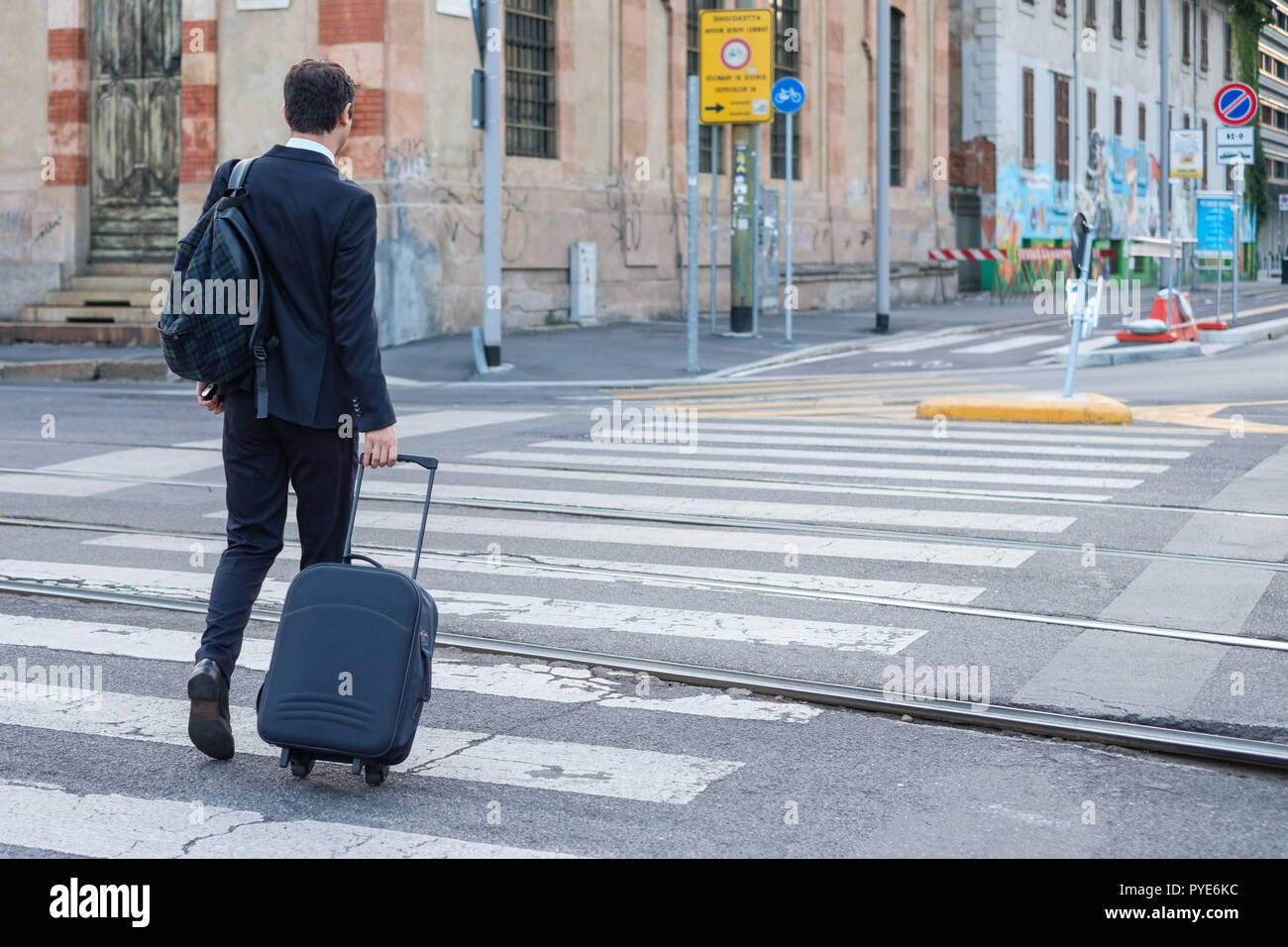 Businessman with travel luggage walking in the city street Stock Photo