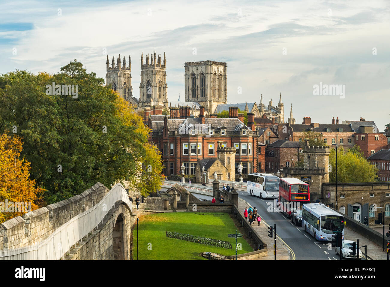 Scenic autumn York cityscape - historic landmarks, medieval walls, sunlit Minster towers, Lendal Bridge, people walking - North Yorkshire, England UK. Stock Photo