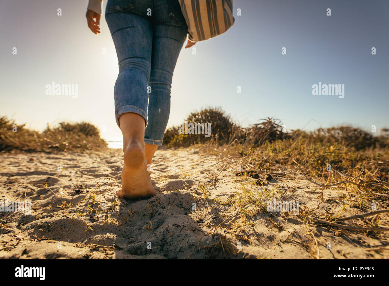 Low angle close up of a woman walking bare feet on beach sand wearing a bag Stock Photo Alamy