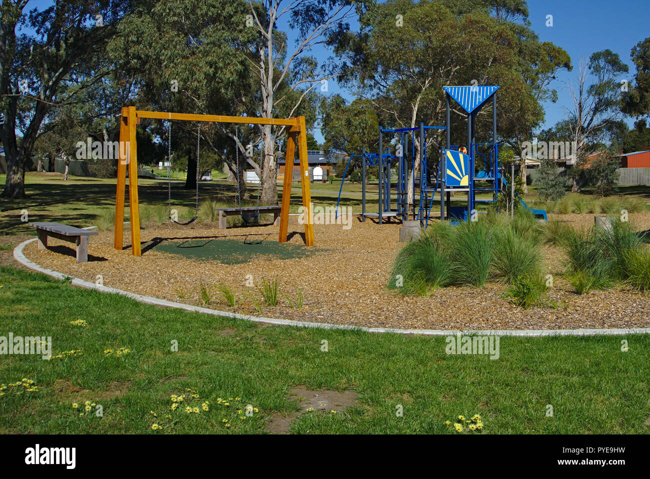 Empty playground at public park during daytime with lots of trees and blue sky Stock Photo
