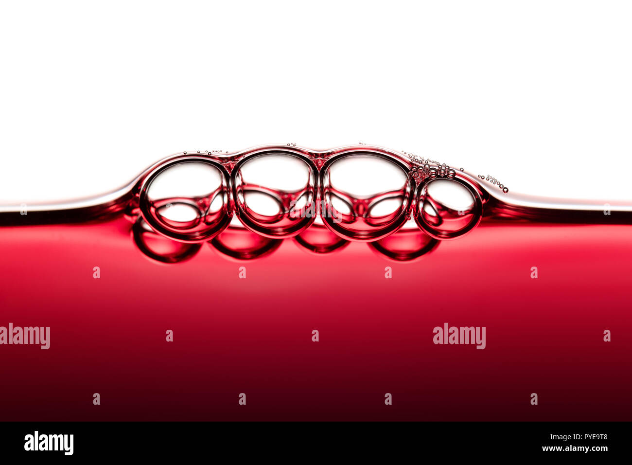 Abstract Food Art Pattern of Symmetrical Red Wine Bubbles photographed close-up against white background Stock Photo