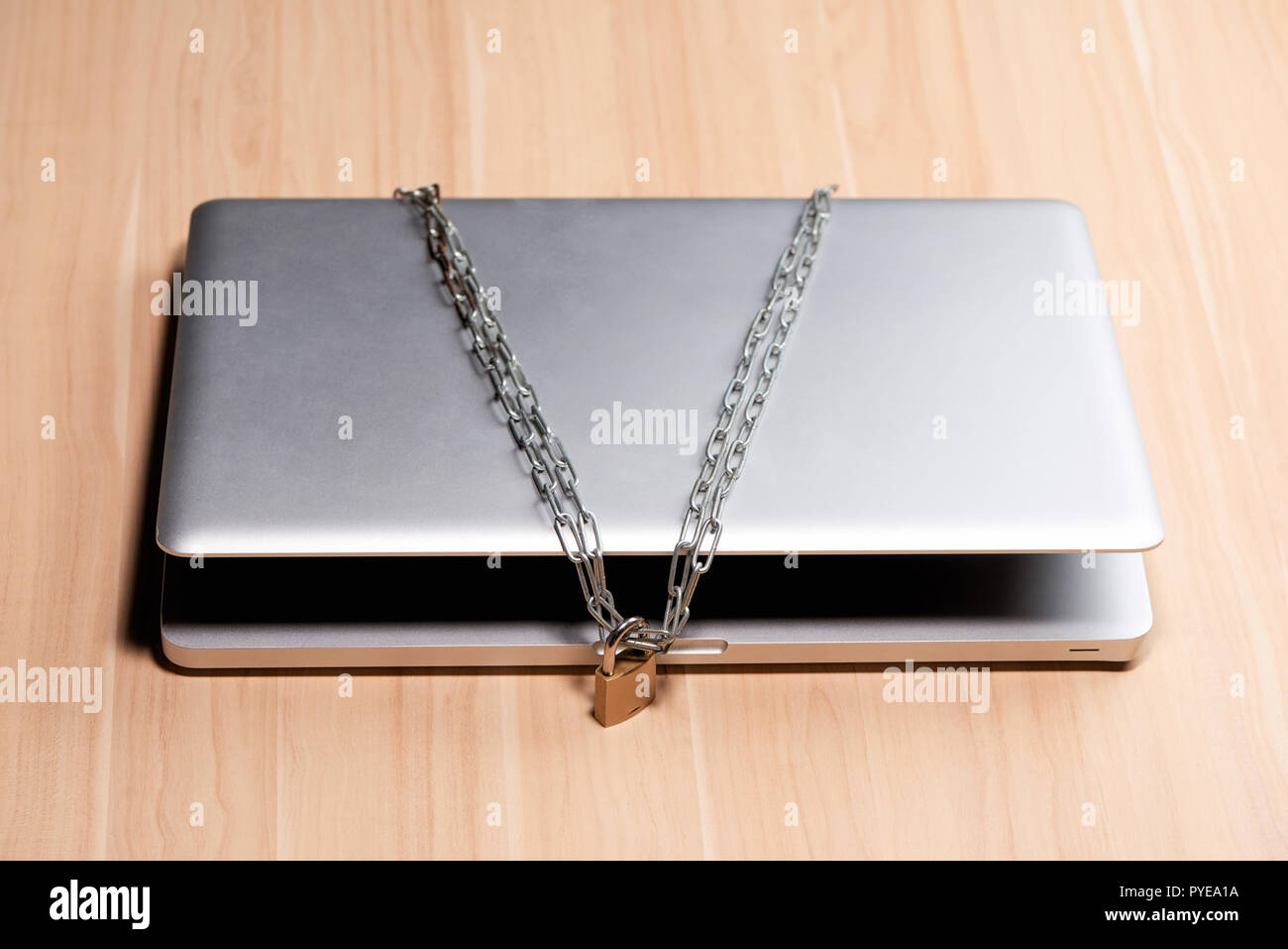 Heavy chain with a padlock around a laptop on table. Stock Photo