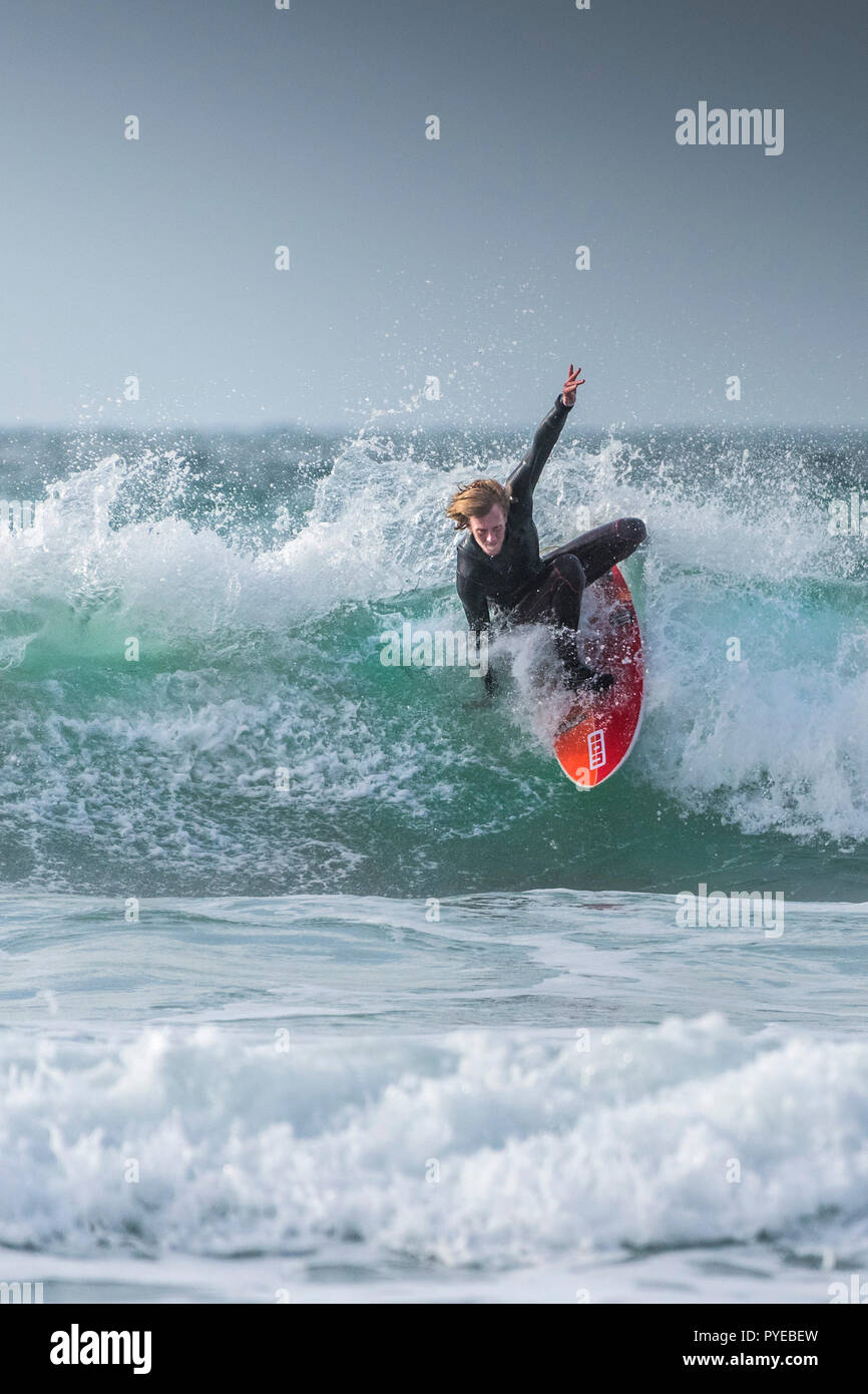 A surfer riding a wave in cold weather at Fistral in Newquay in Cornwall. Stock Photo