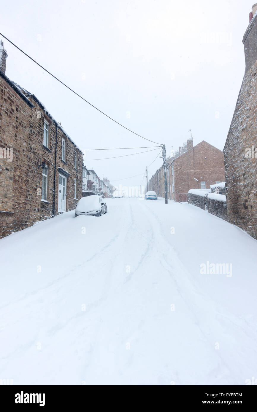 Looking up a hill with terraced houses on both sides, during heavy snow fall, Consett, County Durham, England, UK Stock Photo