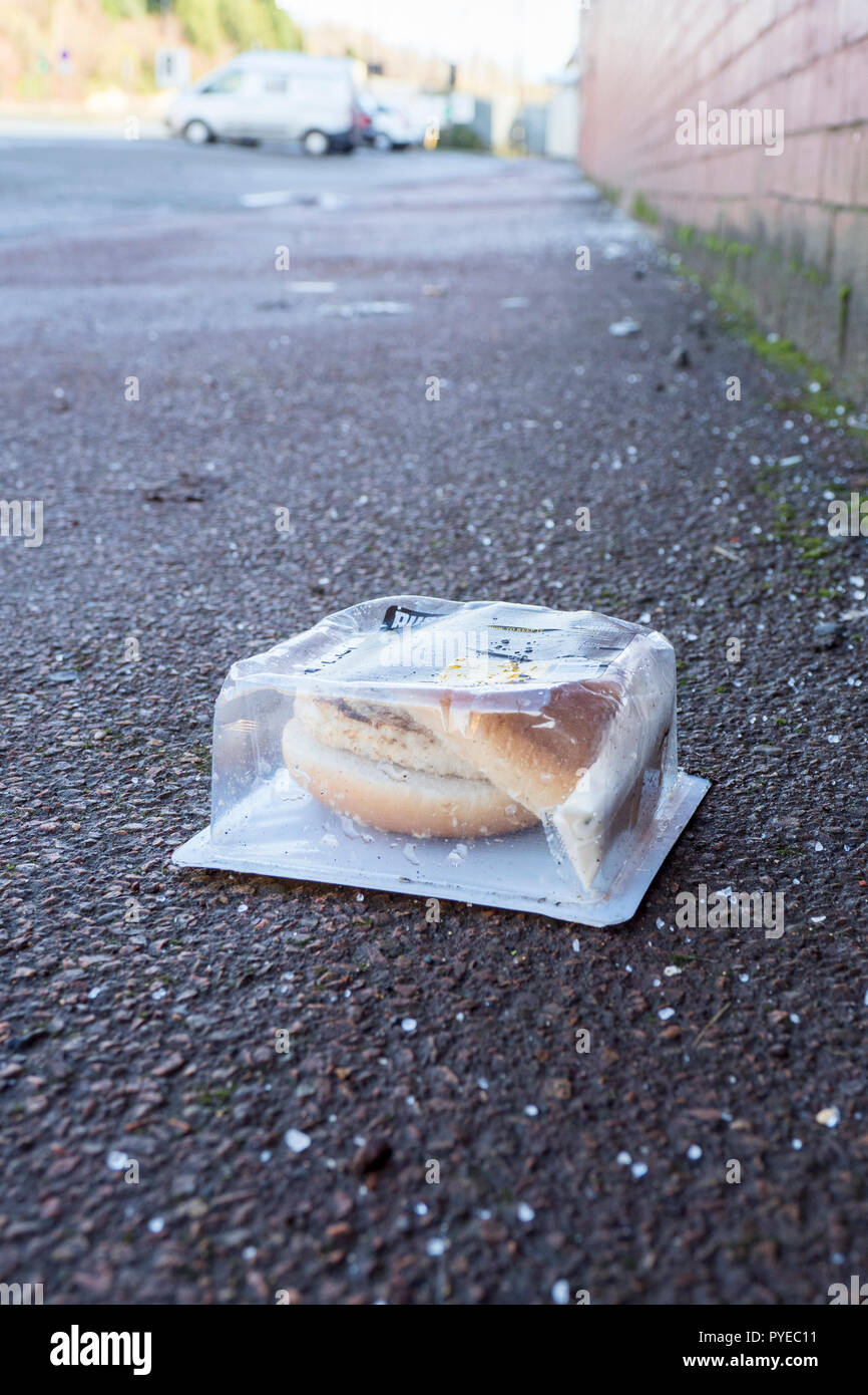 Discarded microwave burger still in plastic wrapper, littering the