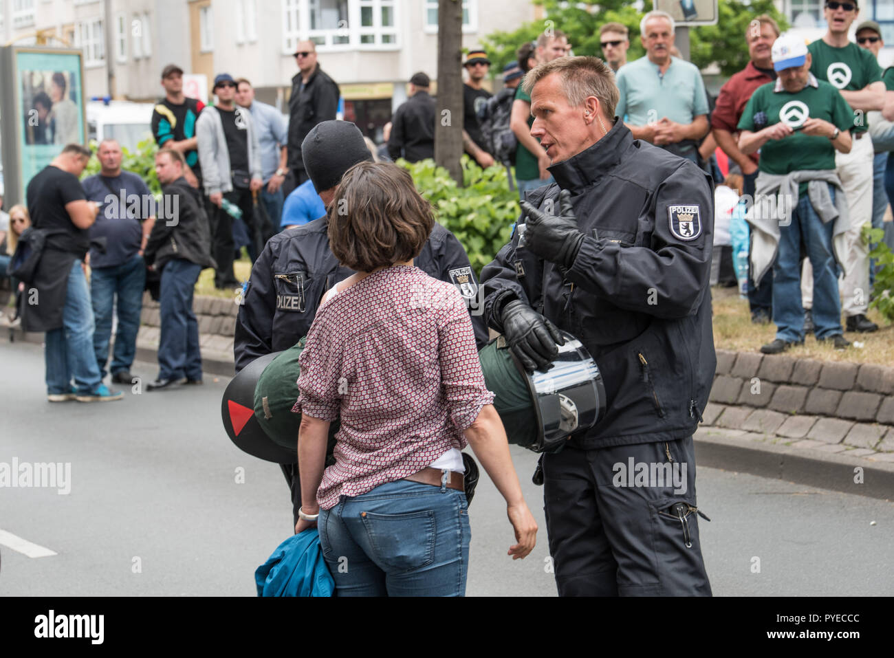 Wütende Frau redet verzweifelt mit 2 Polizisten. Im Hintergrund sind Demonstranten der 'Identitäre Bewegung'. Stock Photo