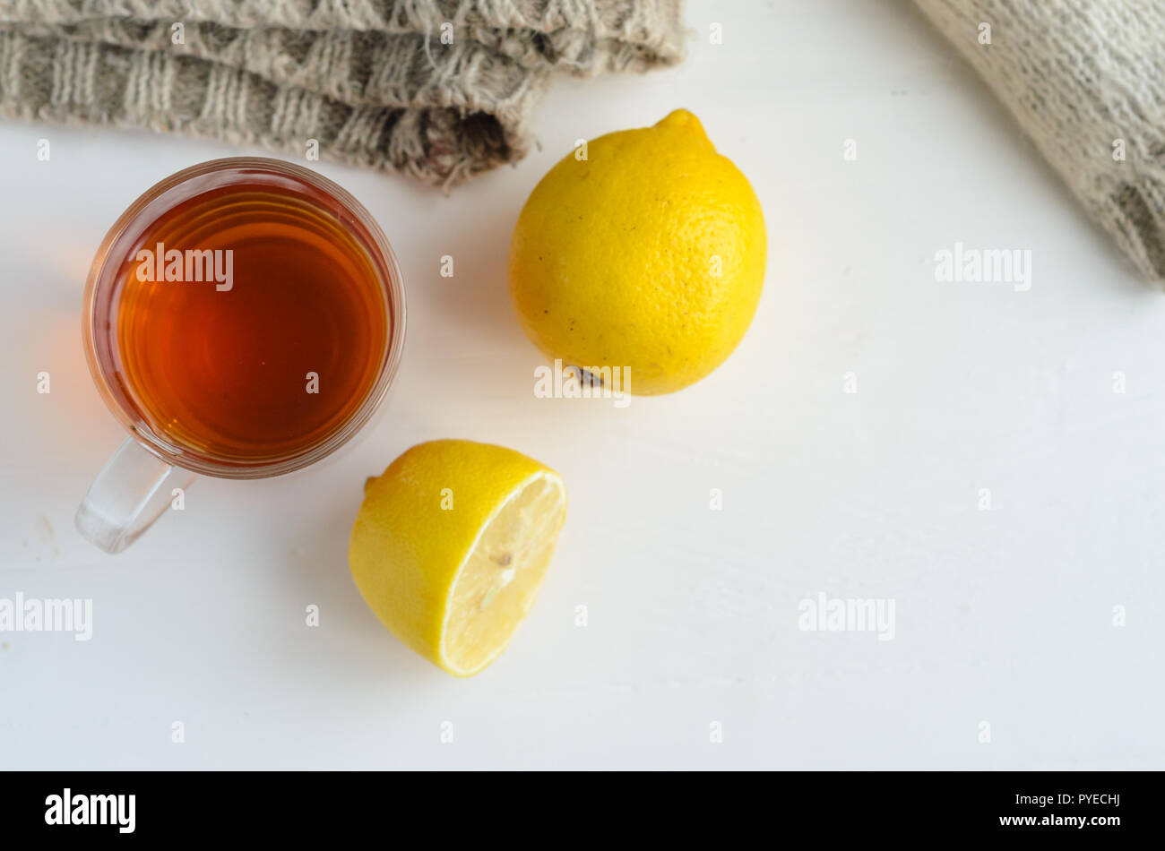 cup of tea , one and half lemon and woolen sweater on white wooden background.Protection against colds.Flatlay view. Stock Photo