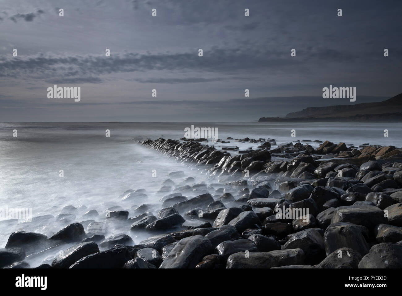 Misty looking sea lapping against wet shiny rocks at Kimmeridge in Dorset, England, UK Stock Photo