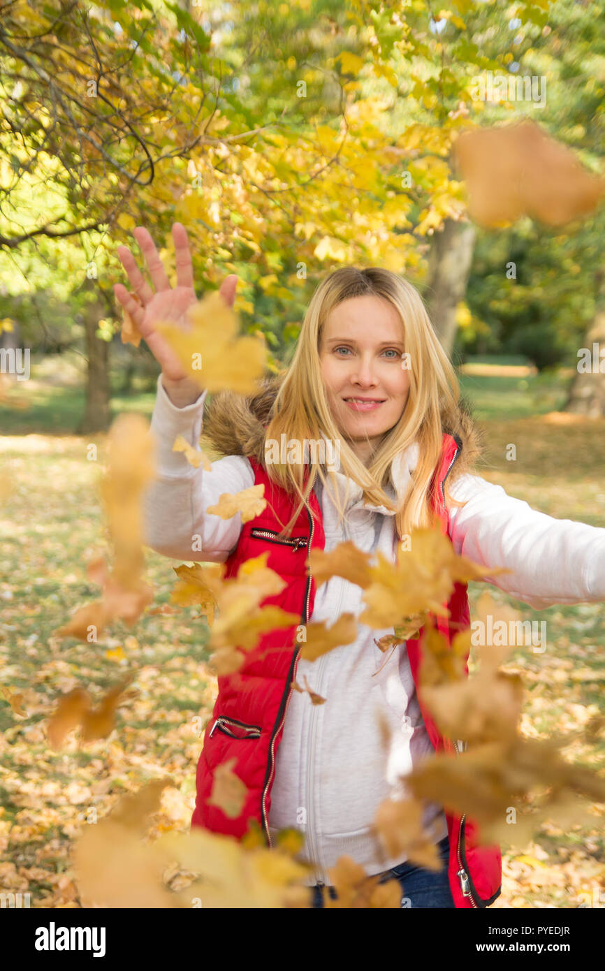 cheerful woman playing with colorful fall leaves in autumn park Stock Photo