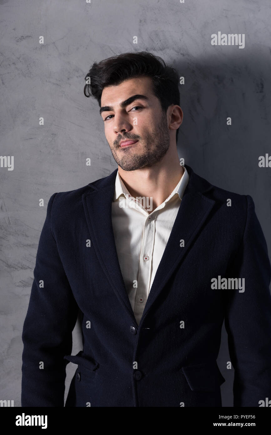 A confident handsome young businessman in a black suit standing in ...