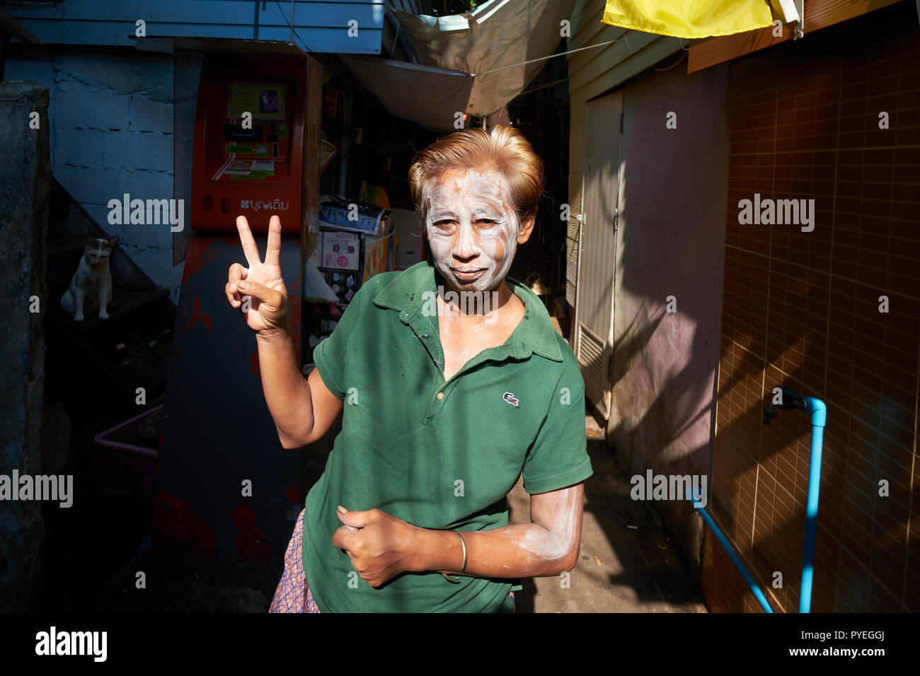 The ubiquitous V sign, performed by a Thai woman in a lower end neighbourhood in Bangkok, Thailand, her face covered in talcum powder to keep cool Stock Photo