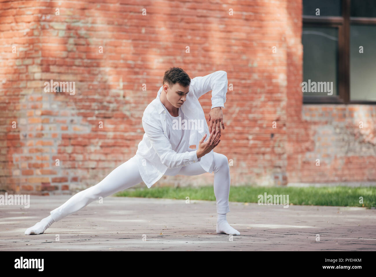 handsome young male dancer in white clothes practicing on street Stock
