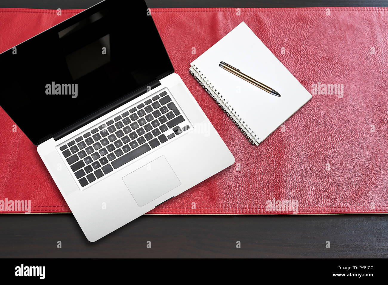Notepad and notebook laptop on Red leather tablecloth, view from above Stock Photo