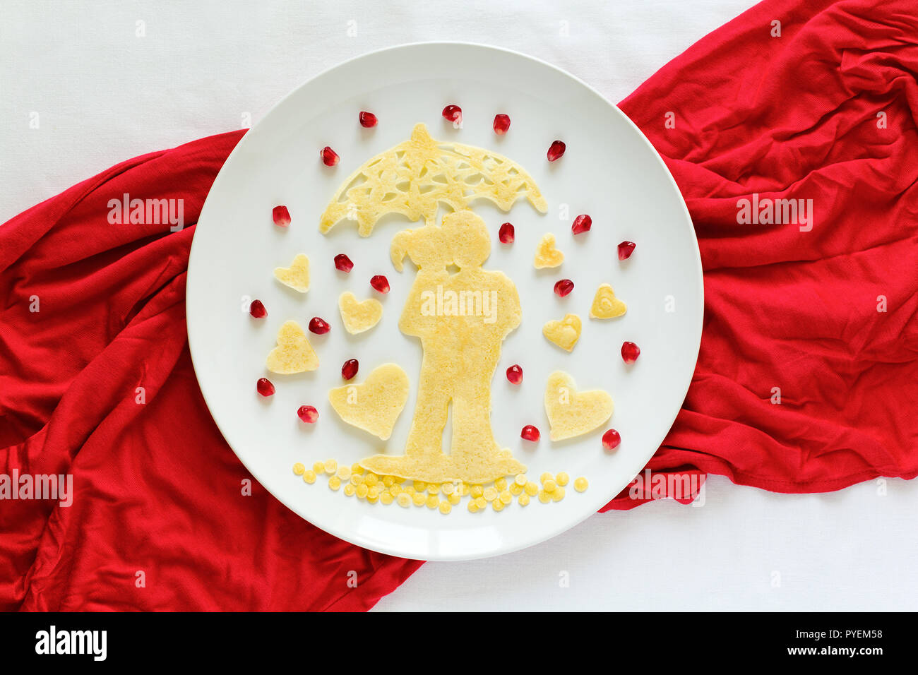 Art food concept. Silhouette of a couple in love under umbrella. Lace pancakes with pomegranate seeds. Top view. Flat lay. Space for copy Stock Photo