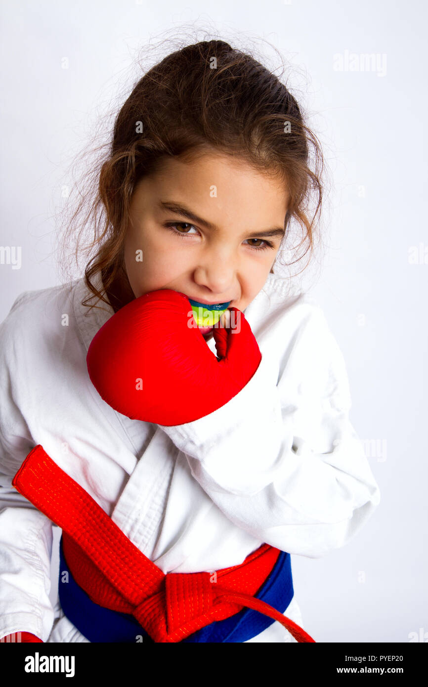 A little karate girl in white kimono and in a red and blue belt at the same  time puts on her mouth guard in preparation for the fight Stock Photo -  Alamy