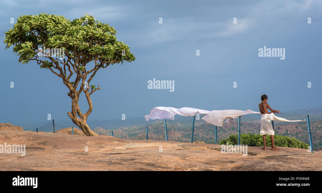A hindu devotee hanging washed linen in Hampi, India. Stock Photo