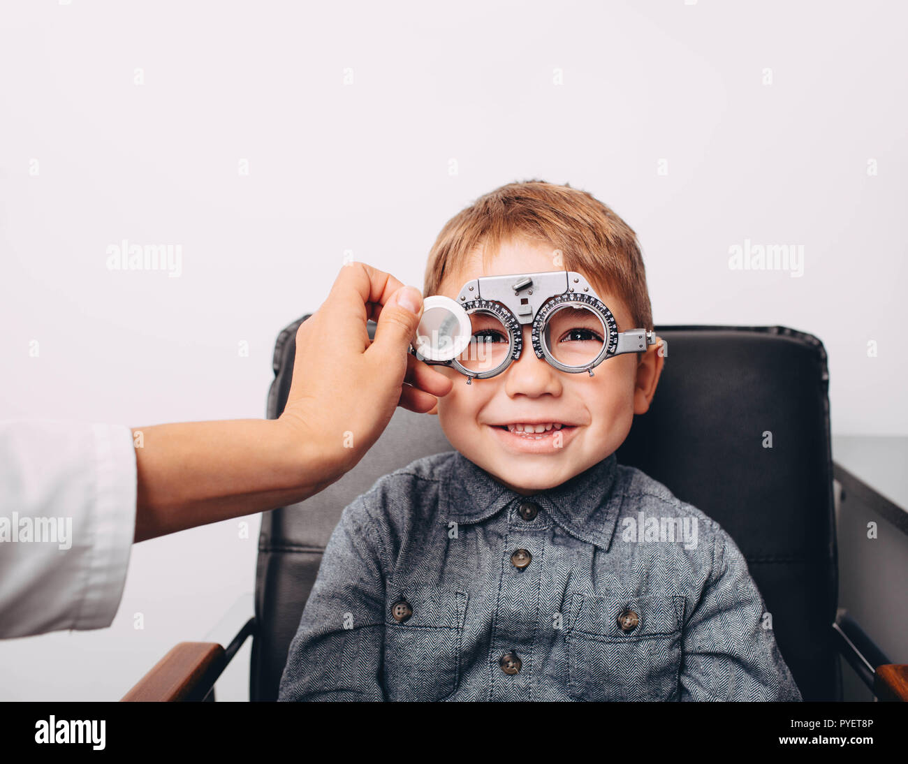 optometrist checking vision of a little cheerful boy using trial frame Stock Photo