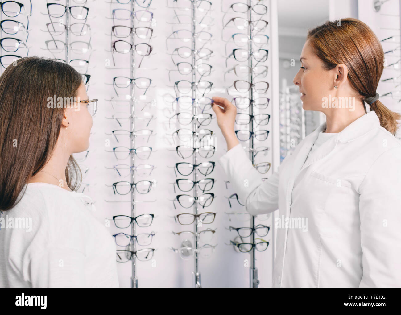 optometrist helps a teenage girl to choosing a new frame for her eyeglasses Stock Photo