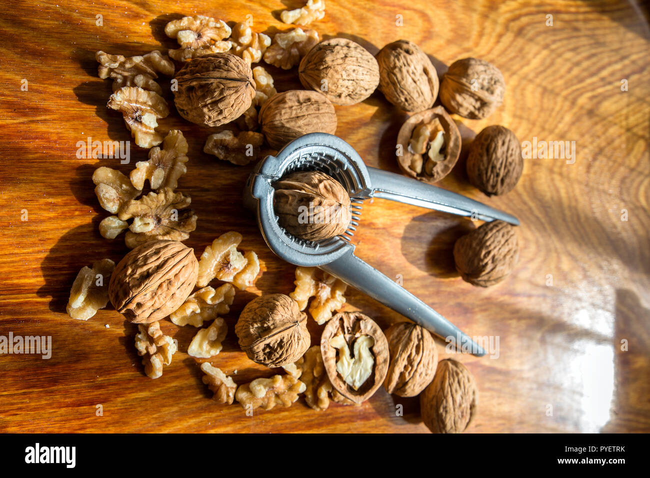 Walnut kernels and whole walnuts  with a nutcracker on wooden table Stock Photo