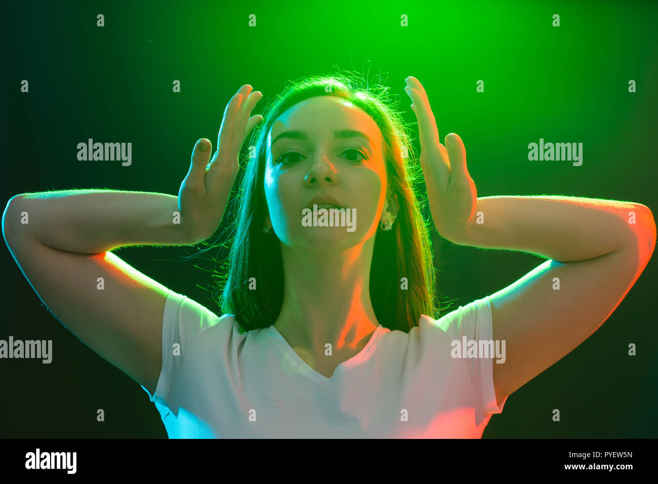 Dance, jazz funk, sport and people concept - young woman dancing in darkness and holds her hands near her face Stock Photo