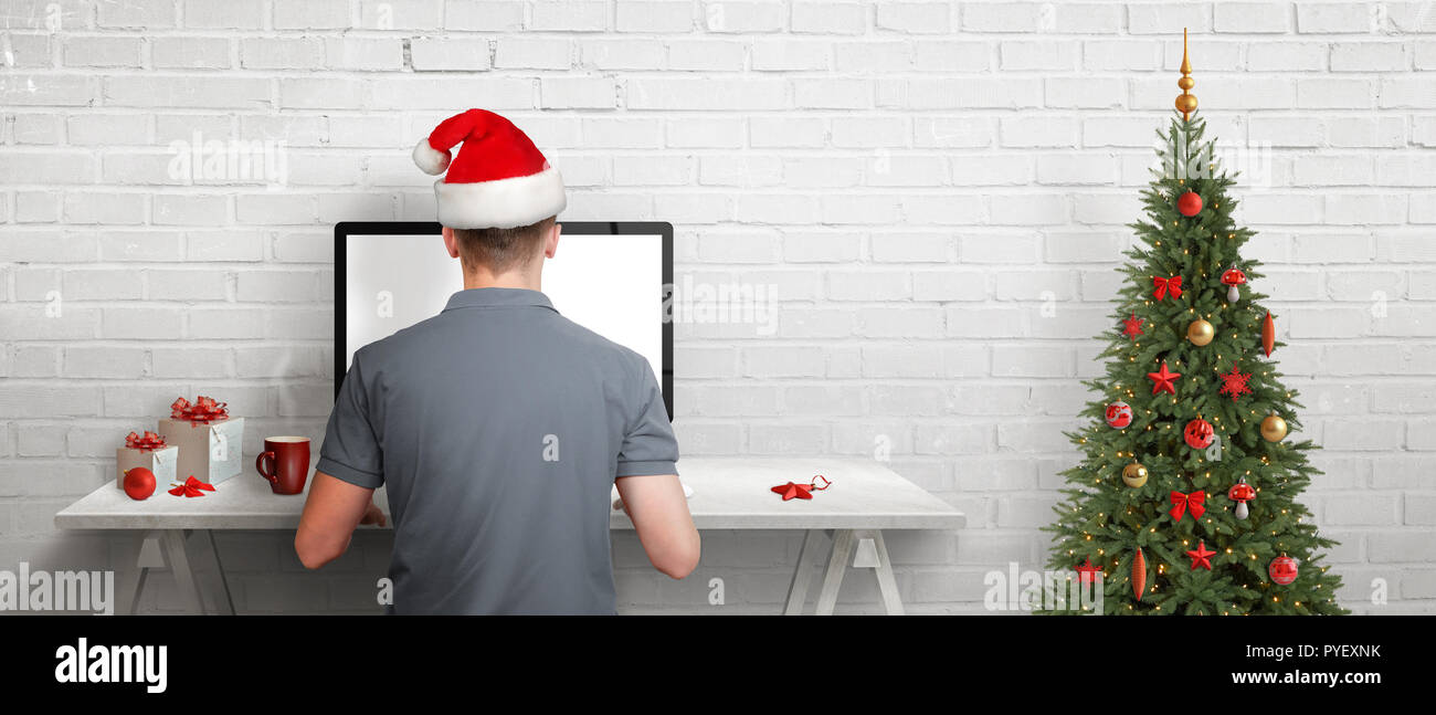 Online shopping during Christmas holidays. Guy sitting at his desk and buying gifts for friends and family on internet. Stock Photo
