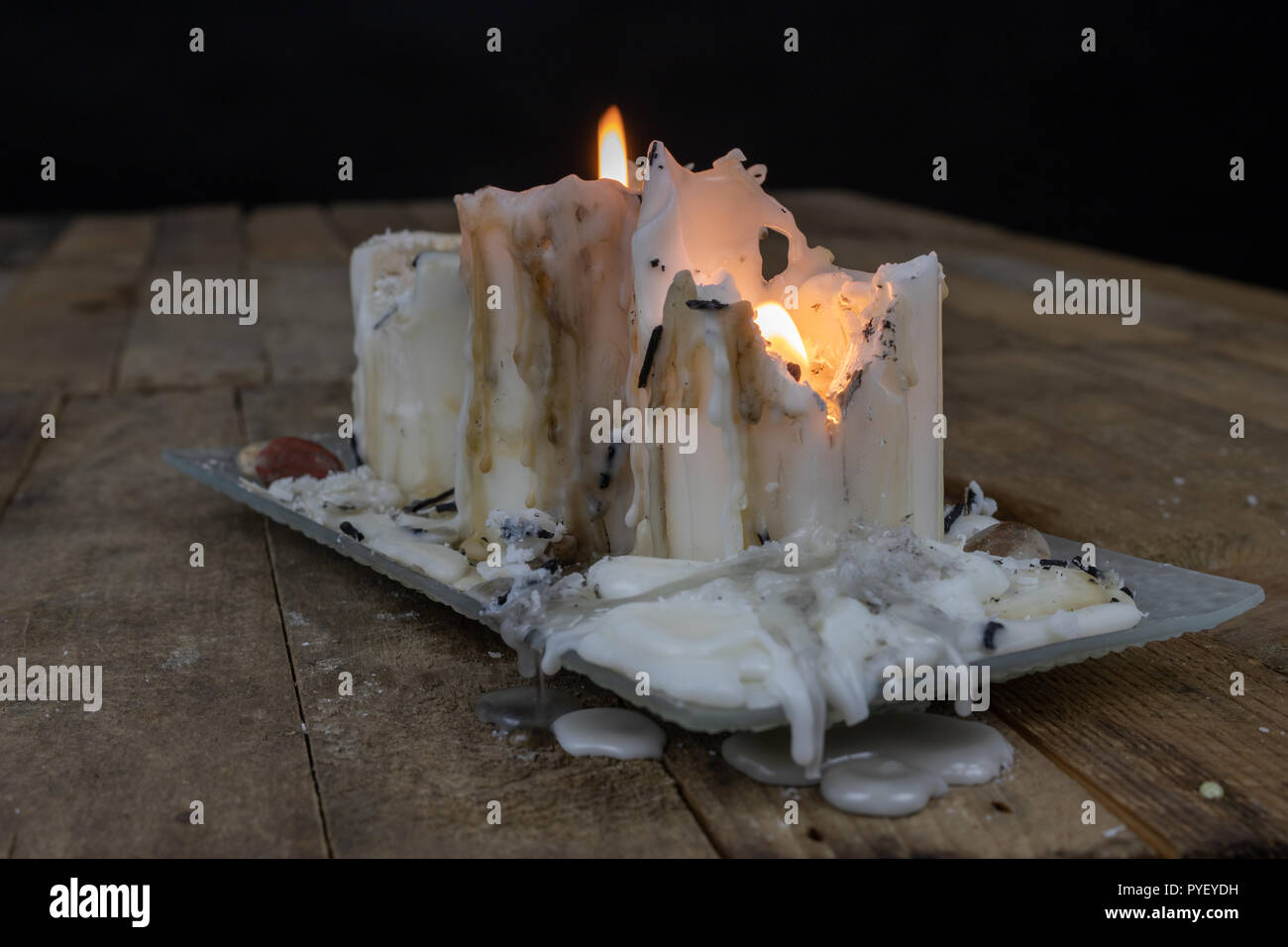 Old candles with dirty wax on a wooden table. Burning dirty