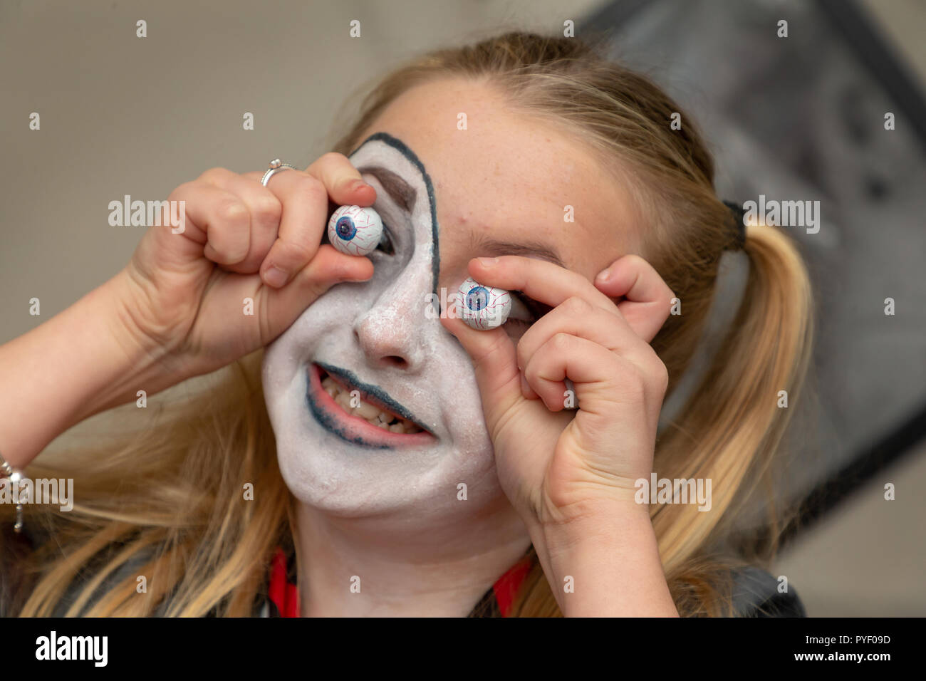 October 2018 - Friends and family in fancy dress at a Halloween Party - Young girl holding chocolate eyeballs to her face Stock Photo