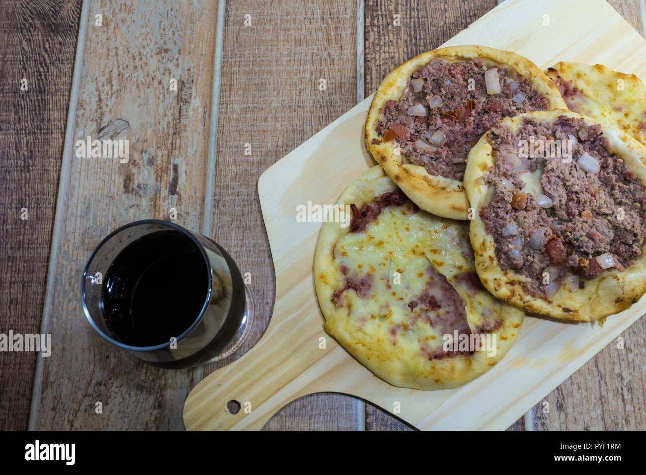 Delicious Arabic Esfiha, with fillings cheese and meat with tomato and onion. Served on a wooden board. Stock Photo
