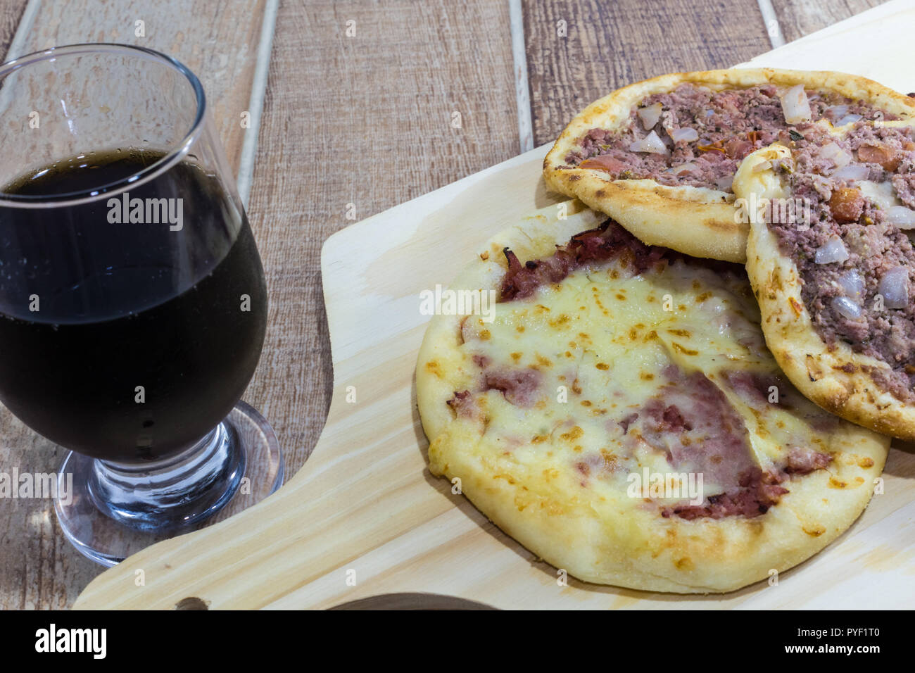 Delicious Arabic Esfiha, with fillings cheese and meat with tomato and onion. Served on a wooden board. Stock Photo