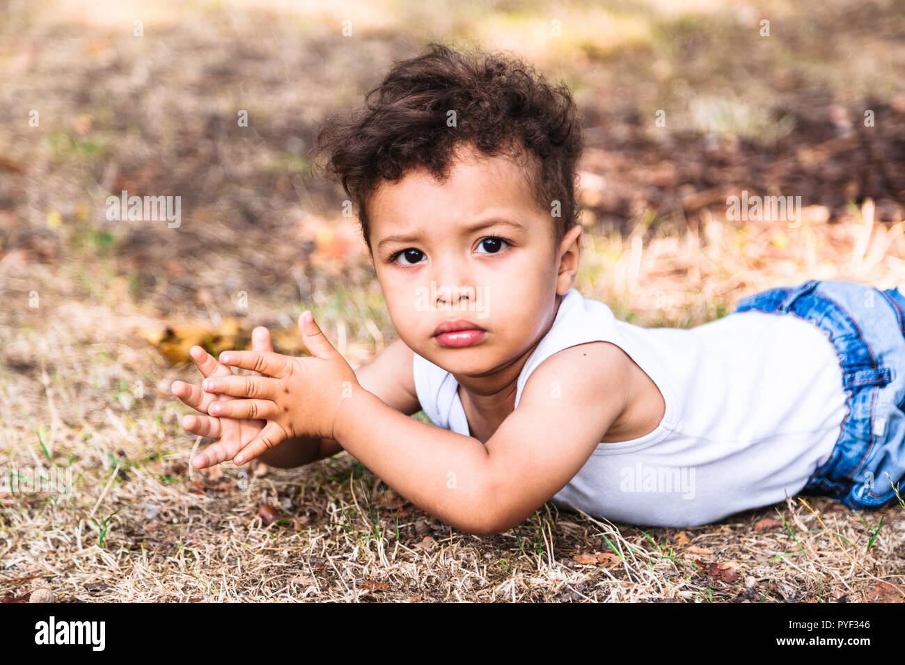 Little boy laying on his stomach on the ground in park outdoor Stock