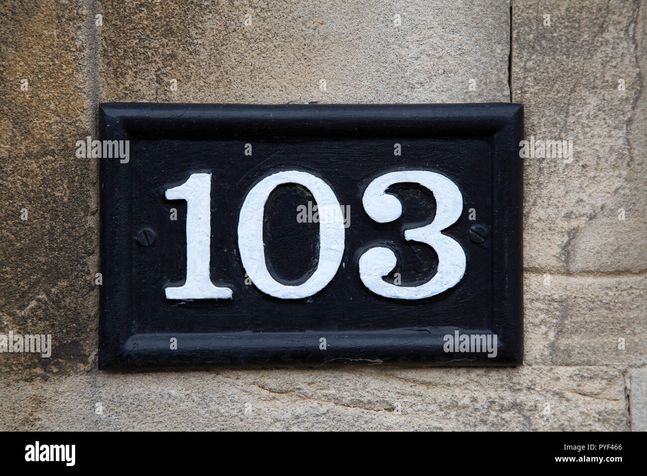 One Hundred and Three Number Sign on Stone Wall Stock Photo