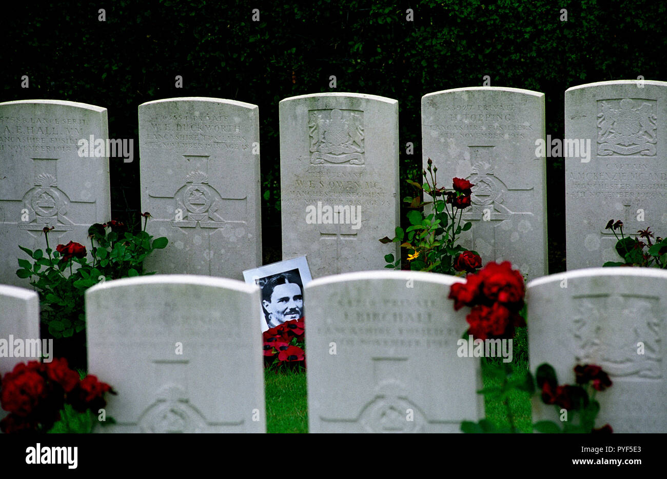 Wilfred Owen the poet died on 4th November 1918 just 7 days before the end of the first world war. A photograph of Owen normally rests against his grave at Ors Communal Cemetery  in the Commonwealth WarGraves Commission plot. The town of Ors is a commune in the Nord department in northern France can be seen in the background and the spot where Owen died is just behind the Church spire in the background of this photograph. Owen was killed in action on 4 November 1918 during the crossing of the Sambre–Oise Canal, exactly one week (almost to the hour) before the signing of the Armistice which end Stock Photo