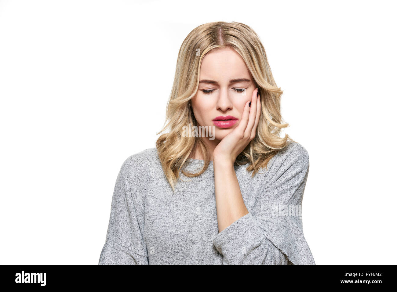Young Woman Suffering From Toothache. Tooth Pain And Dentistry background. Beautiful Young Woman Suffering From Terrible Teeth Pain, Touching Cheek Wi Stock Photo