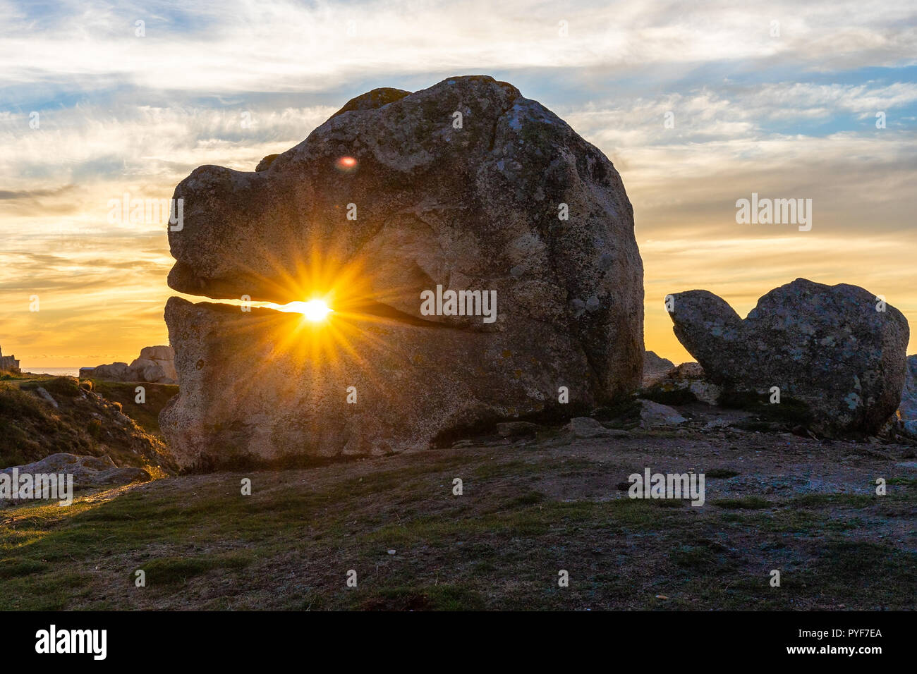 Sunset behind a strange huge rock with beast face and turtle shape stone on the coastline of Ushant island, Brittany, France Stock Photo