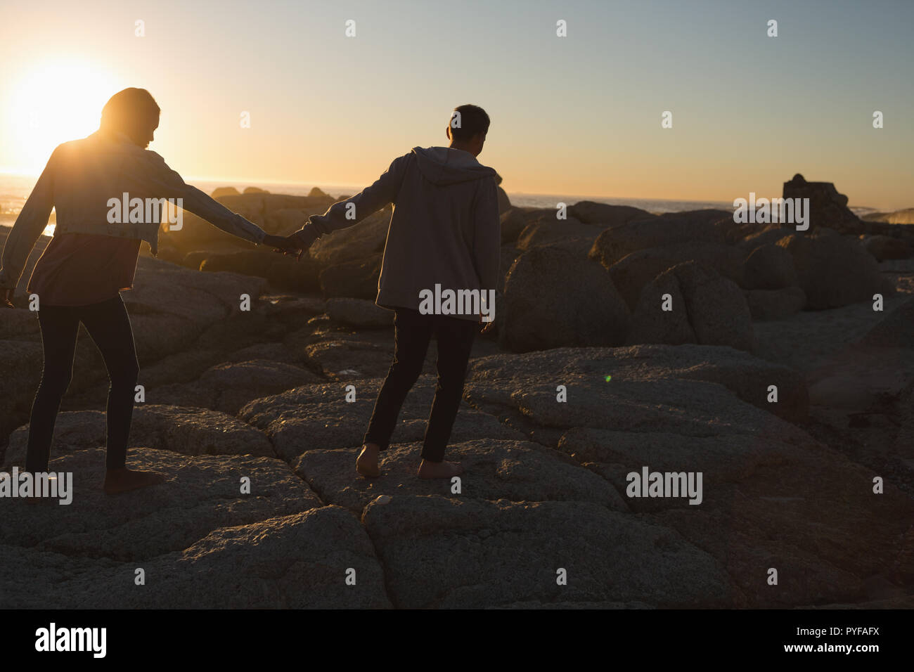 Couple holding hands walking on beach Stock Photo