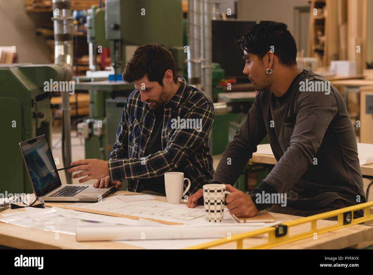Two craftsman discussing over laptop in workshop Stock Photo