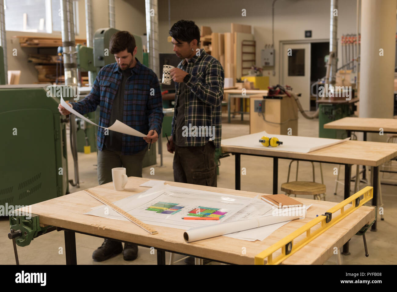 Two craftsman discussing over a blueprint Stock Photo - Alamy