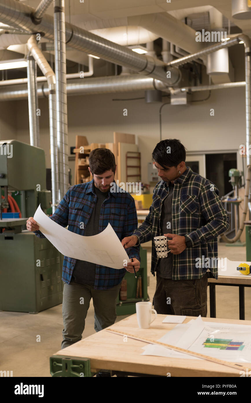 Two craftsman discussing over a blueprint Stock Photo - Alamy