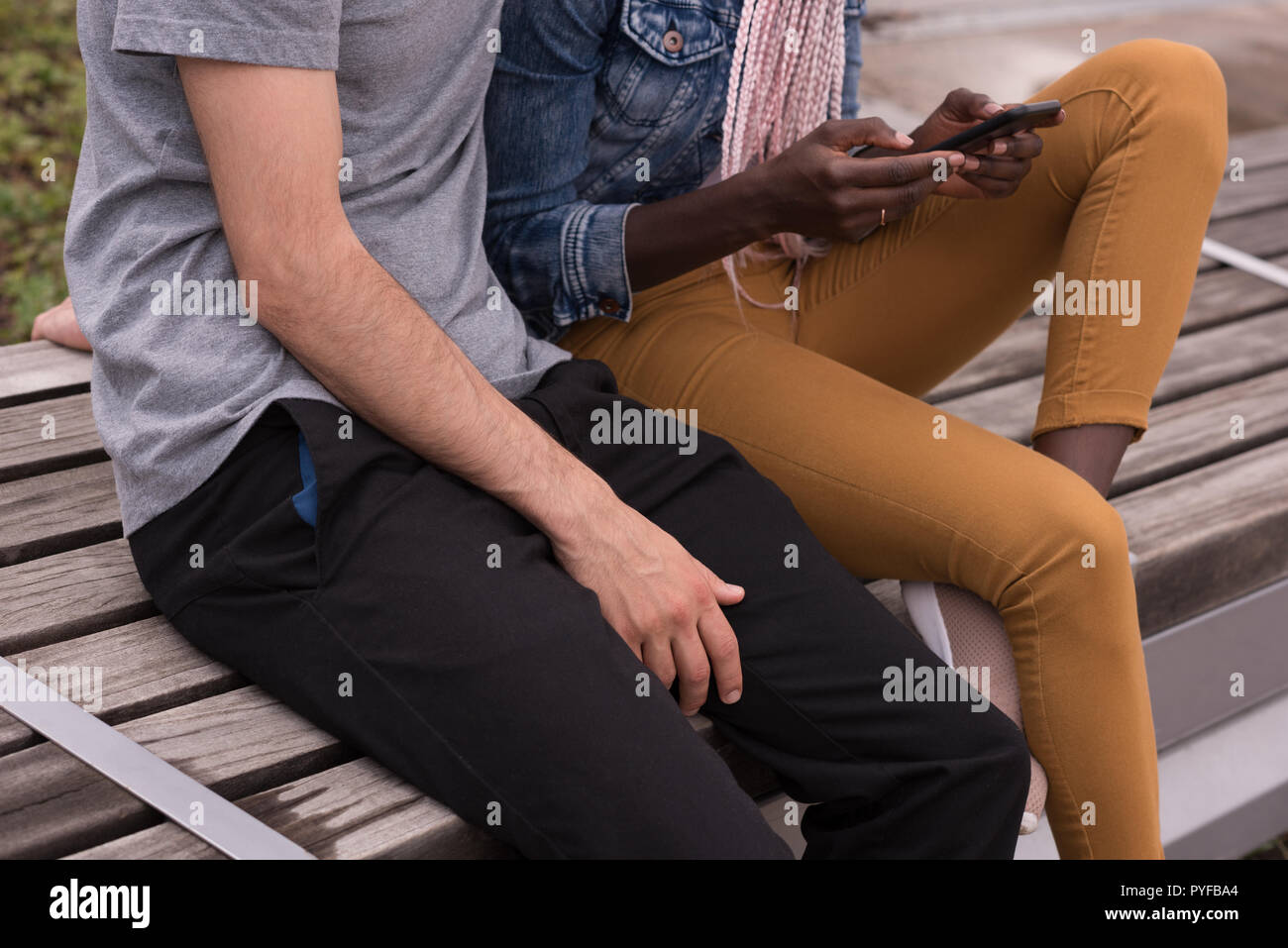 Couple sitting on the bench using mobile phone Stock Photo