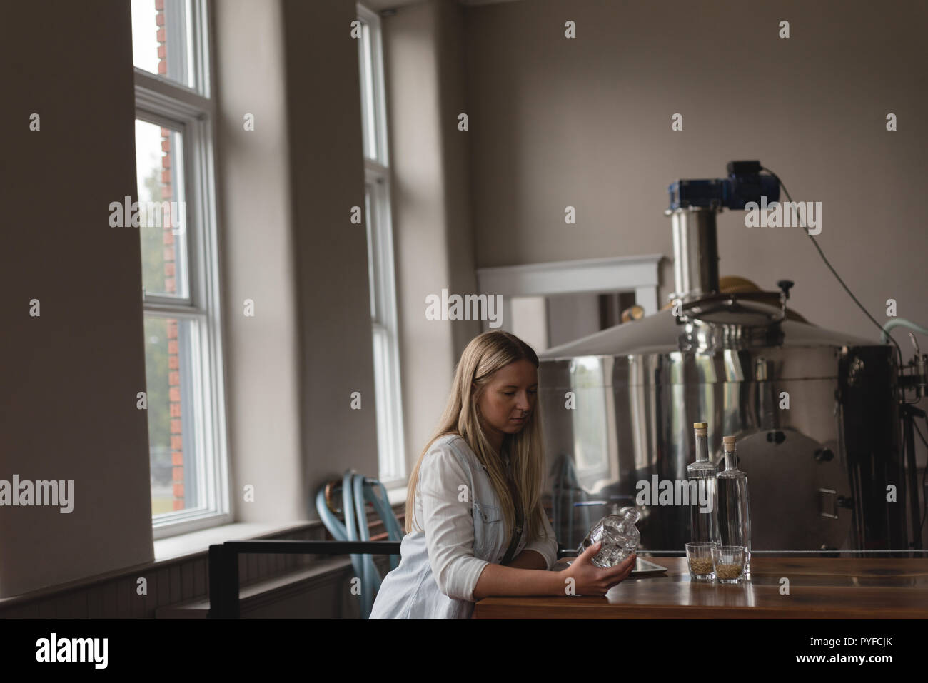 Female worker examining a bottle in factory Stock Photo
