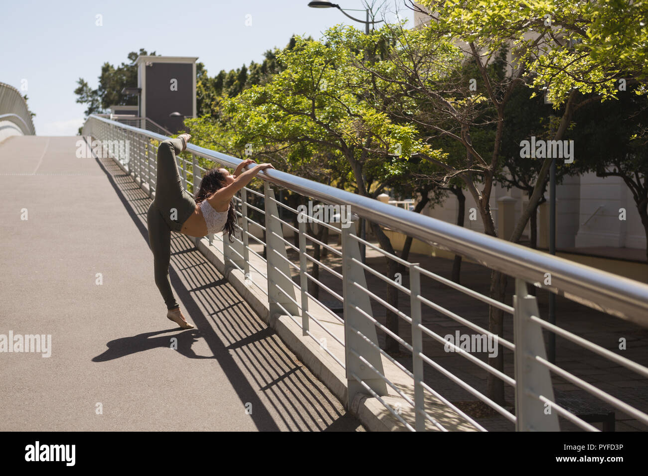 Urban dancer practicing dance on bridge railing Stock Photo