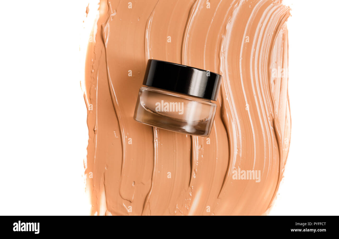 A glass jar of foundation for a face with a sample of the product
