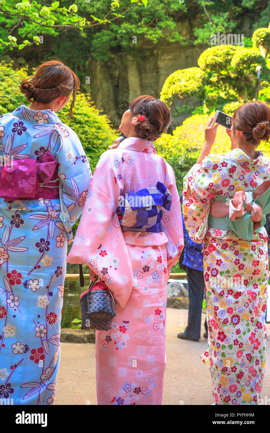 Kamakura, Japan - April 23, 2017: back of Japanese ladies in zen garden, dressed in traditional pink kimonos at Takera Hokoku-ji Temple of Kamakura. Taking selfie of beauty of zen garden,vertical shot Stock Photo