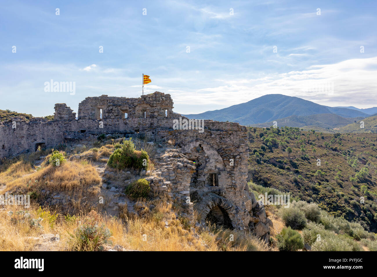 The derelict  castle above the Catalan village of Rodes flying the Catalan flag of independence Stock Photo